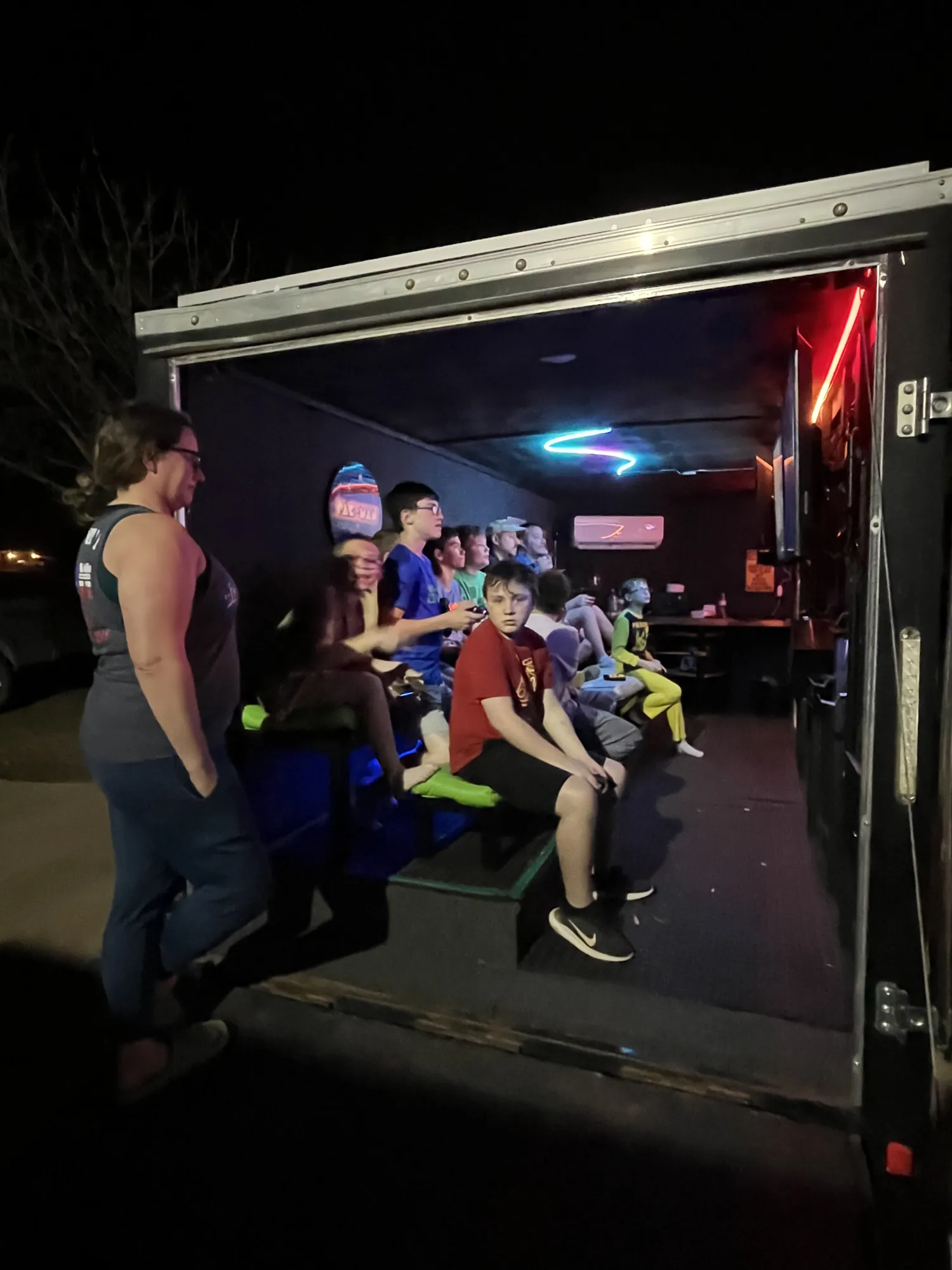 The open trailer glowing at night with kids playing inside