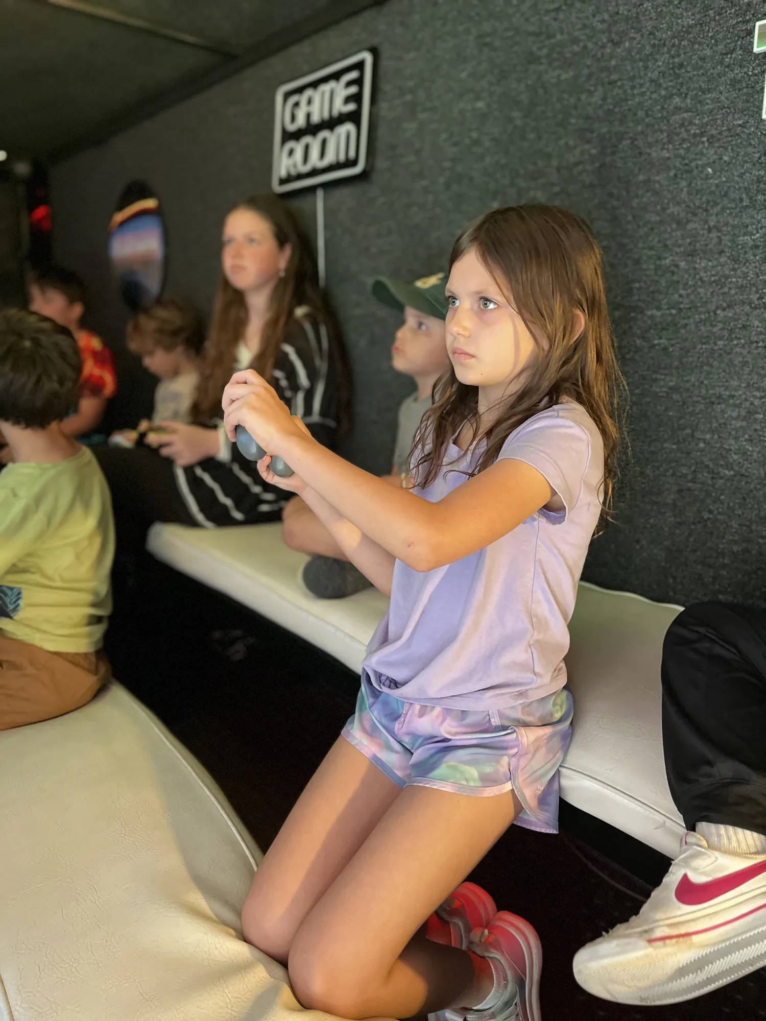 A girl leaning into her game while friends play behind her