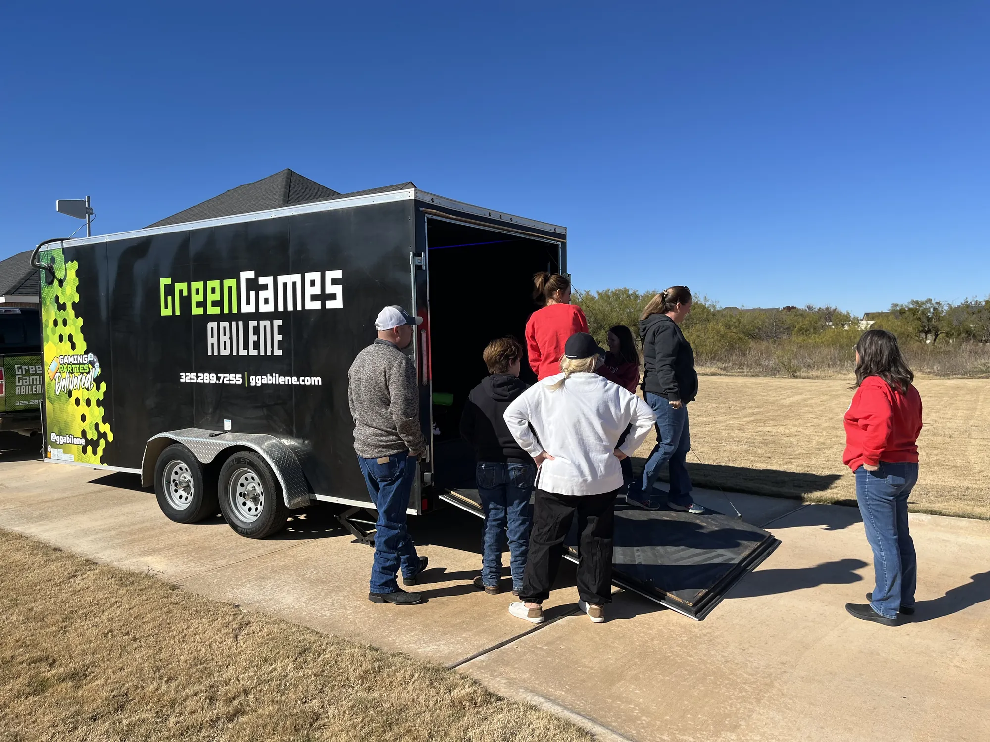 Party guests arriving at the Green Games trailer parked on a sunny day