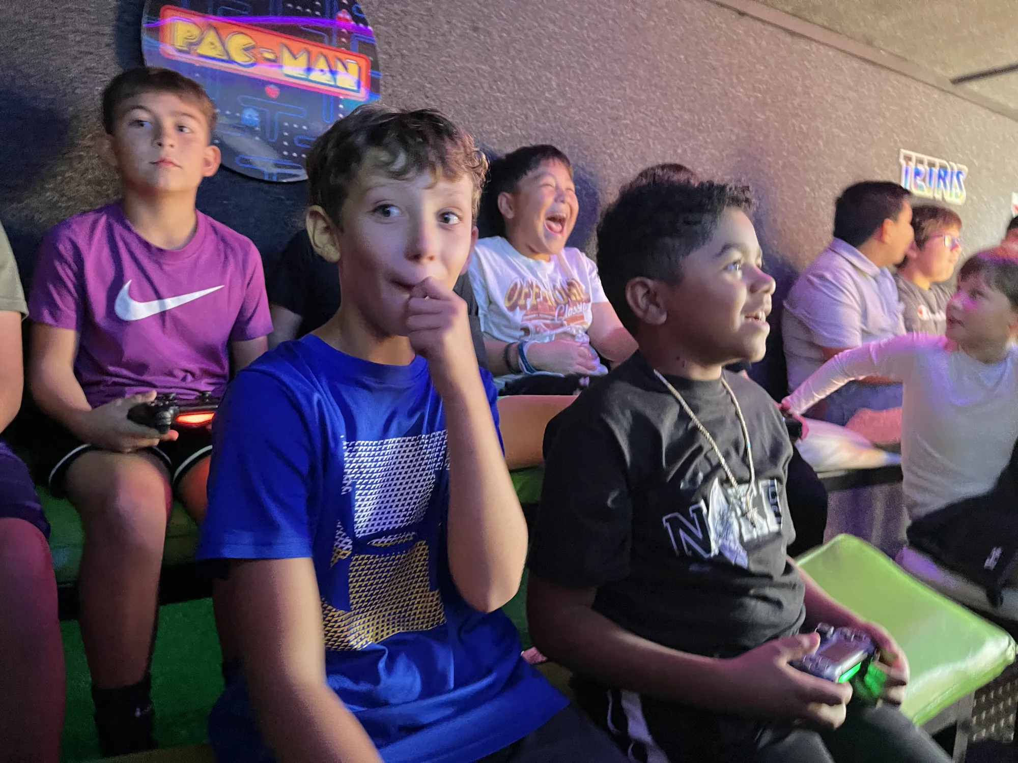 Kids gasping and grinning at the big screens during a video game birthday party in Abilene