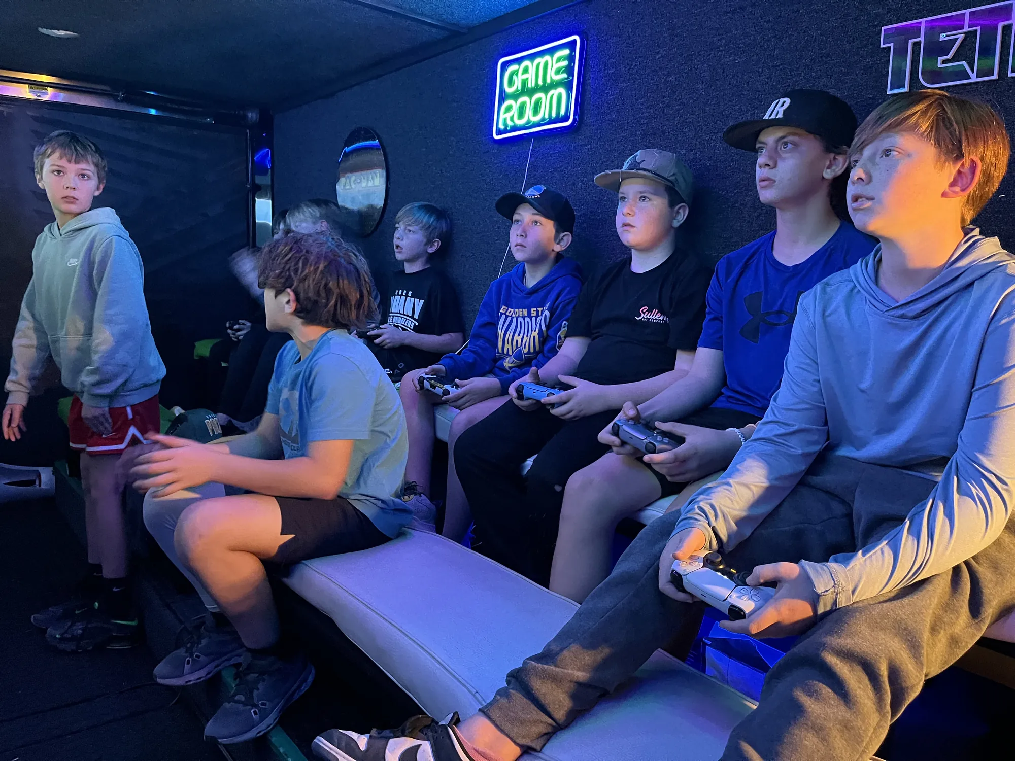 Teens and kids playing in the blue glow of the trailer screens at an evening birthday