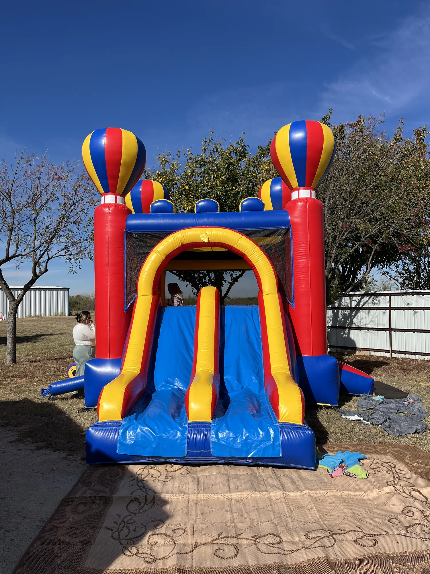 A colorful inflatable bounce house and slide set up in a backyard for a birthday party