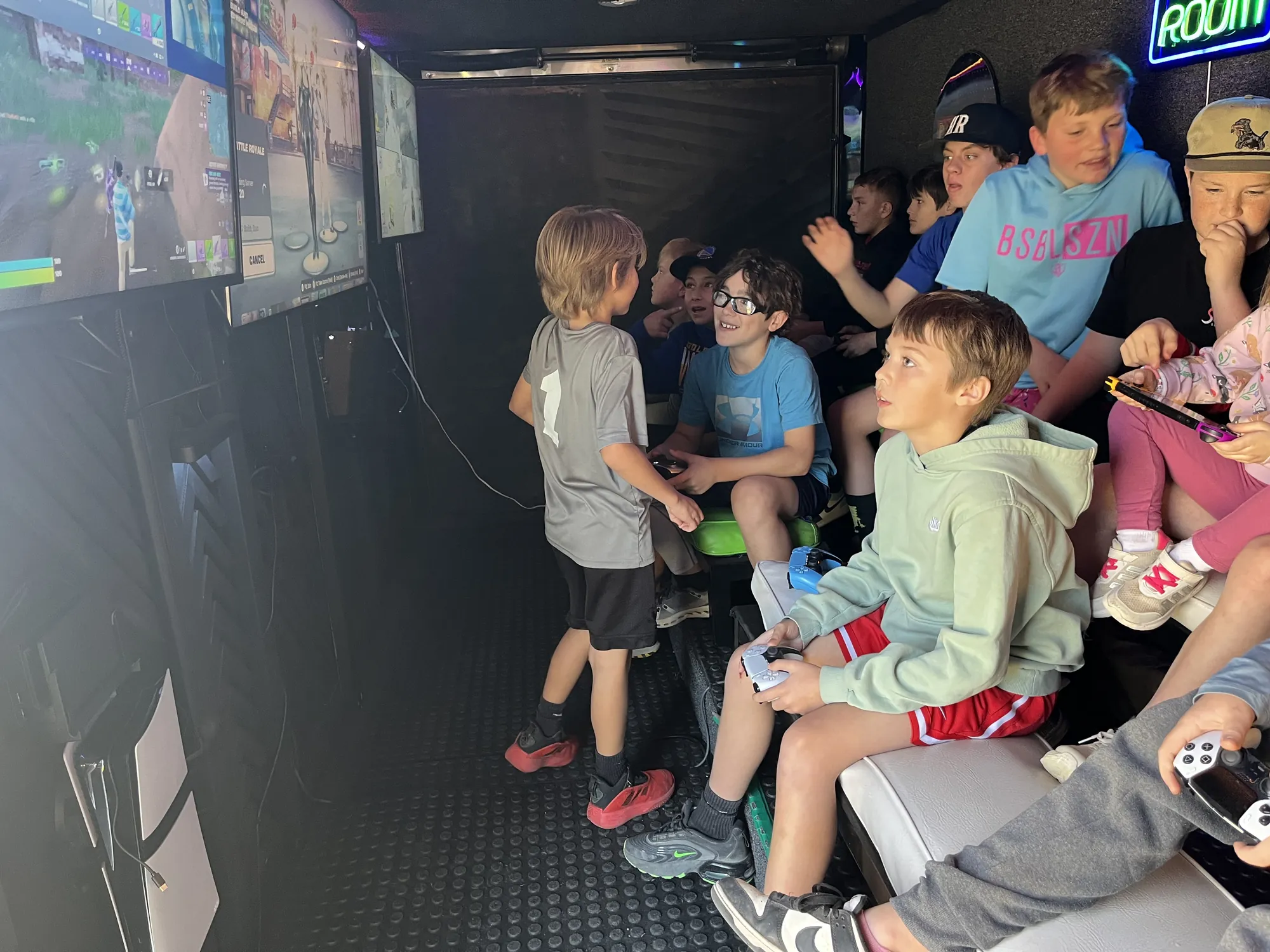 A row of kids playing video games together inside the trailer