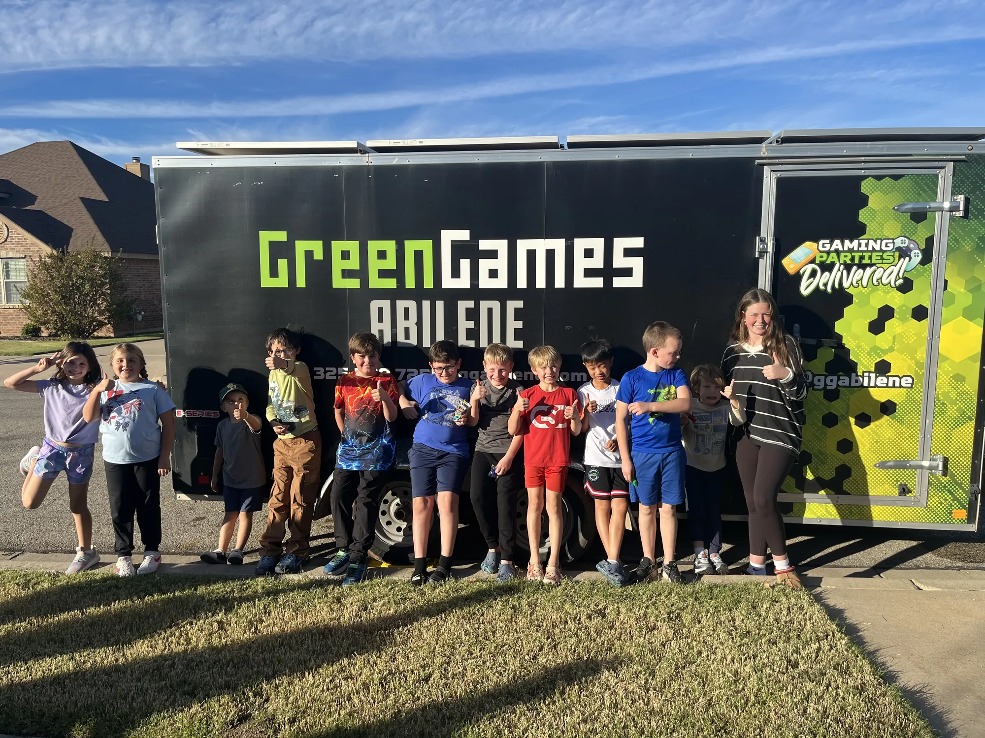 A group of kids lined up in front of the Green Games Abilene video game trailer after a birthday party