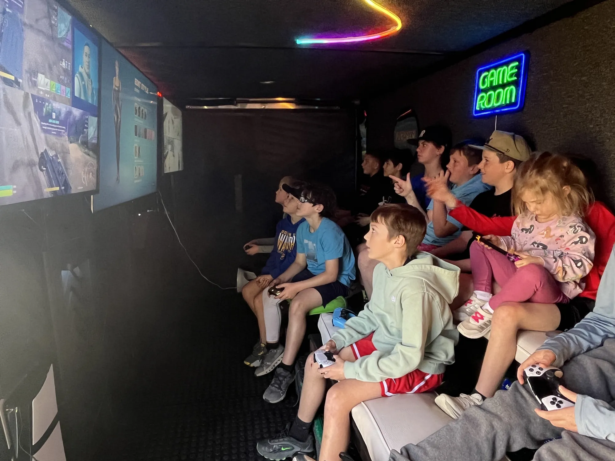 A boy pointing at the screen while his friends play during a birthday party