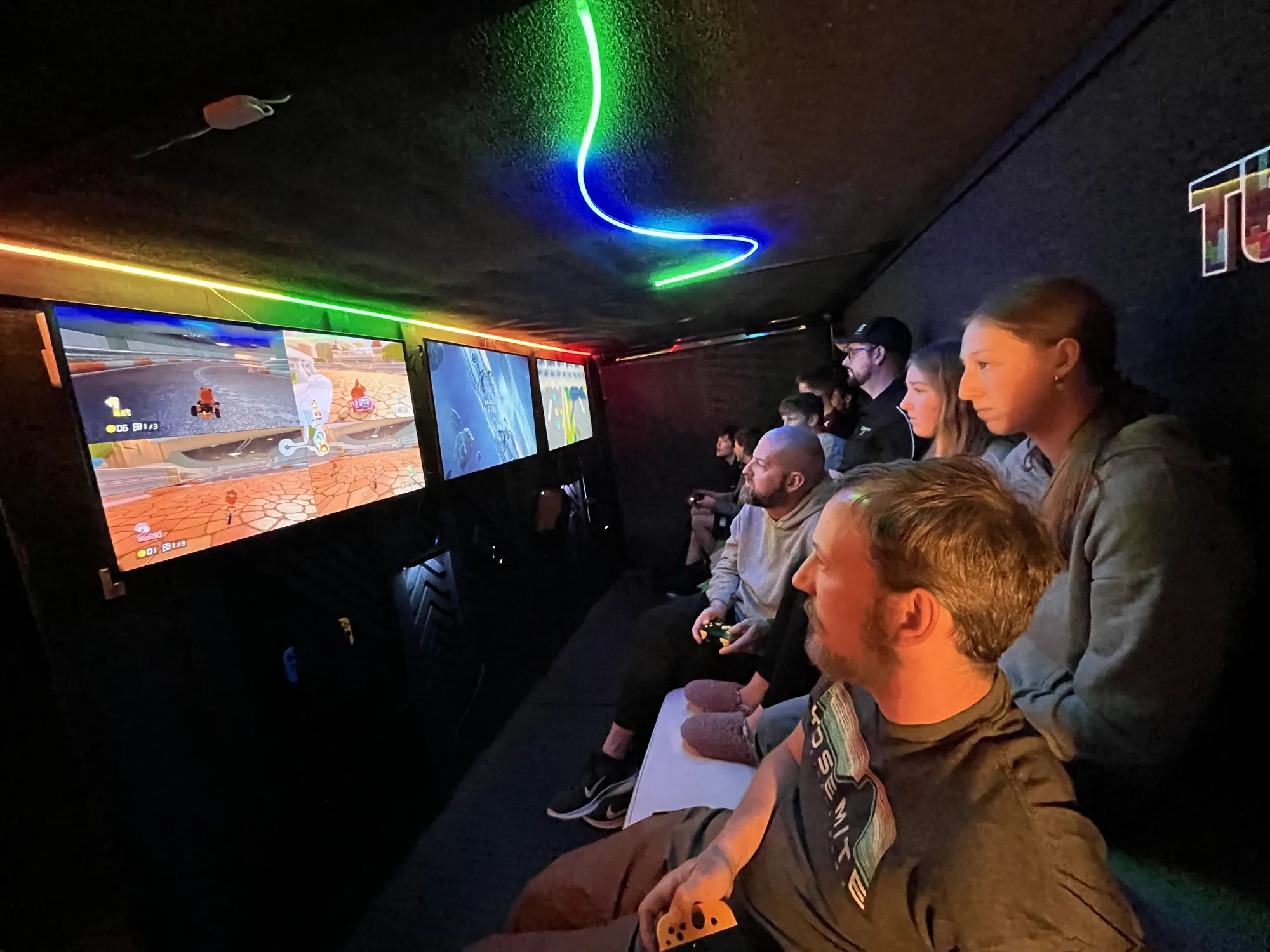 Teens racing on the big screens inside the trailer lit with neon lights