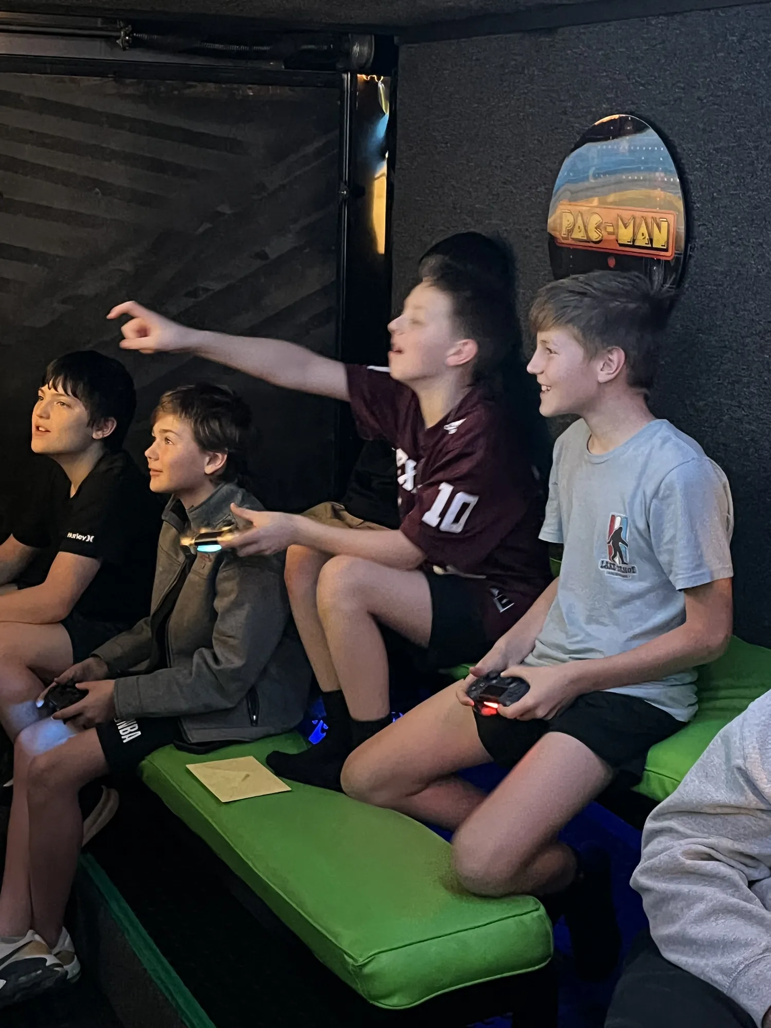 A boy pointing and cheering as his friends play at a teen birthday party