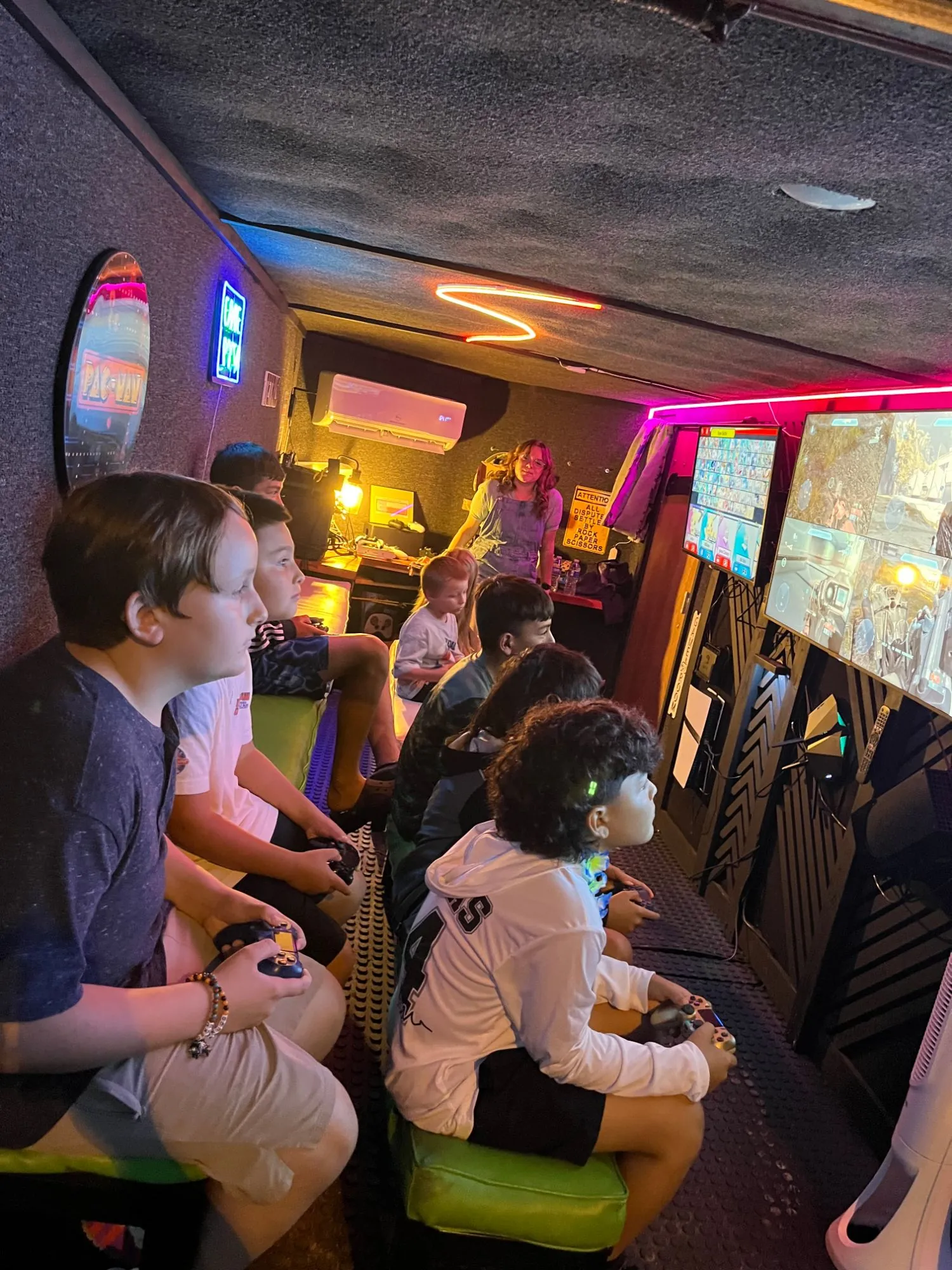Kids playing on the big screens while a Green Games coach helps from the back of the trailer