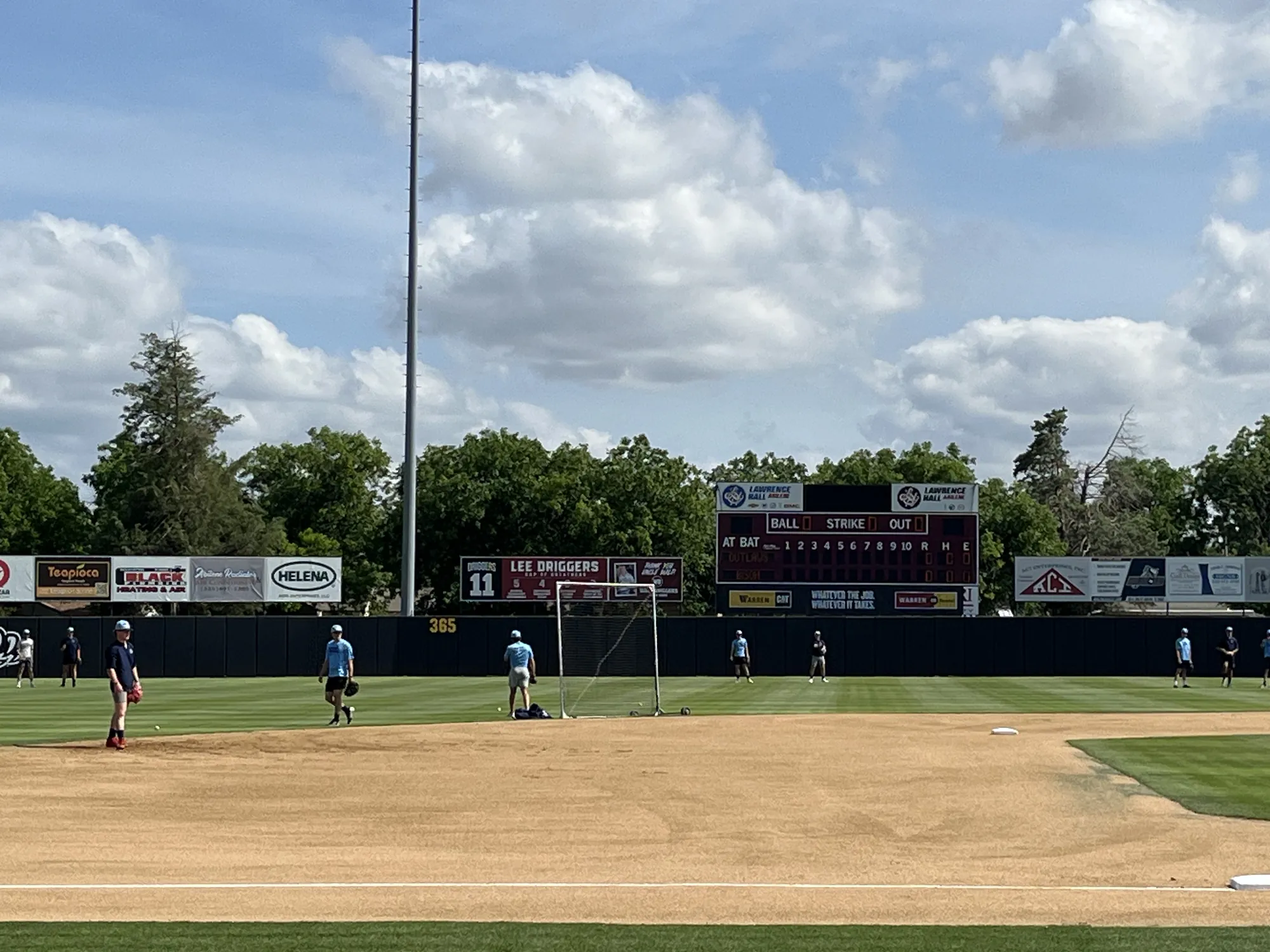 A baseball field with the scoreboard and outfield fences under a cloudy sky