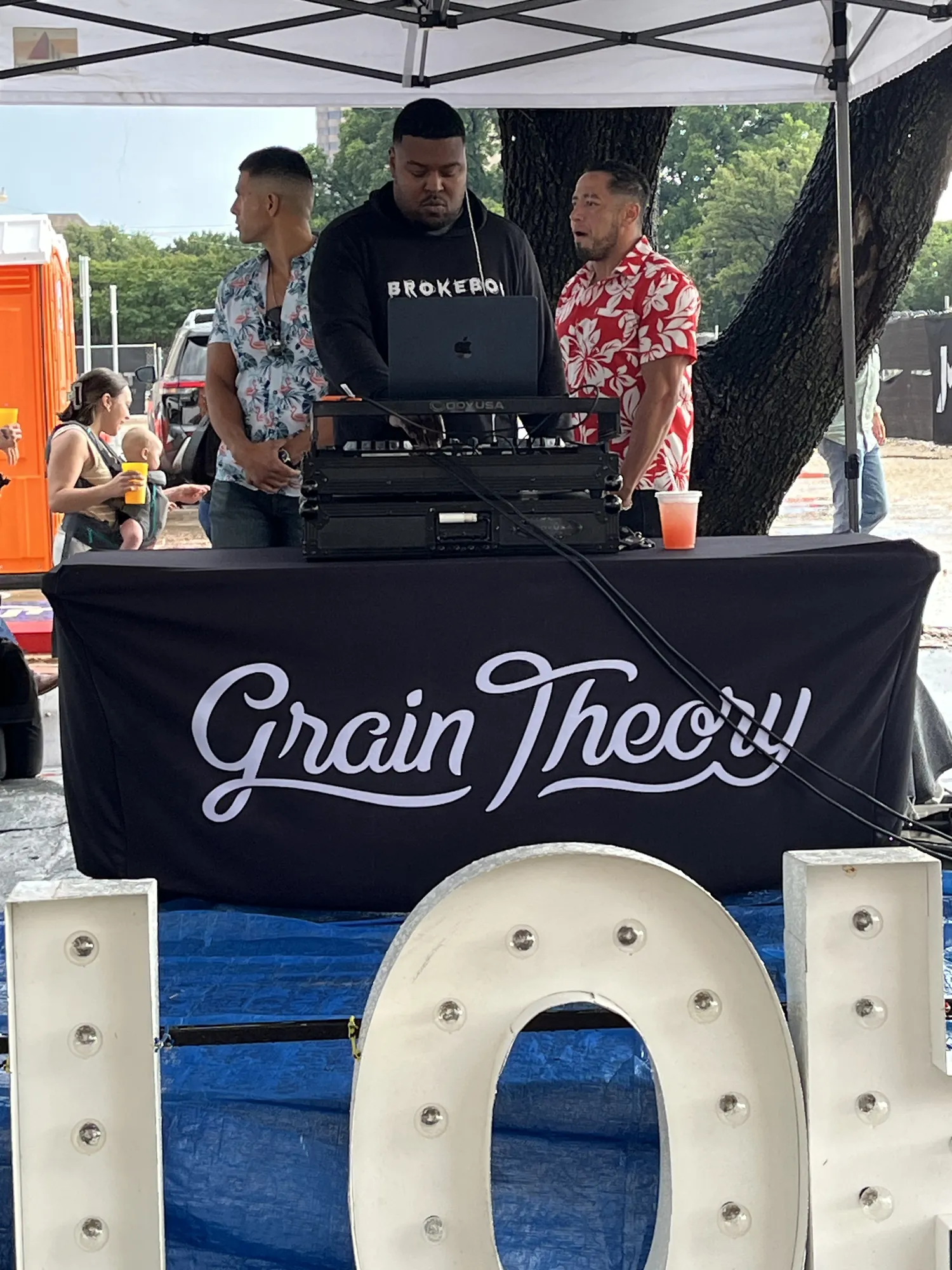 A DJ spinning behind a Grain Theory table at a downtown Abilene block party