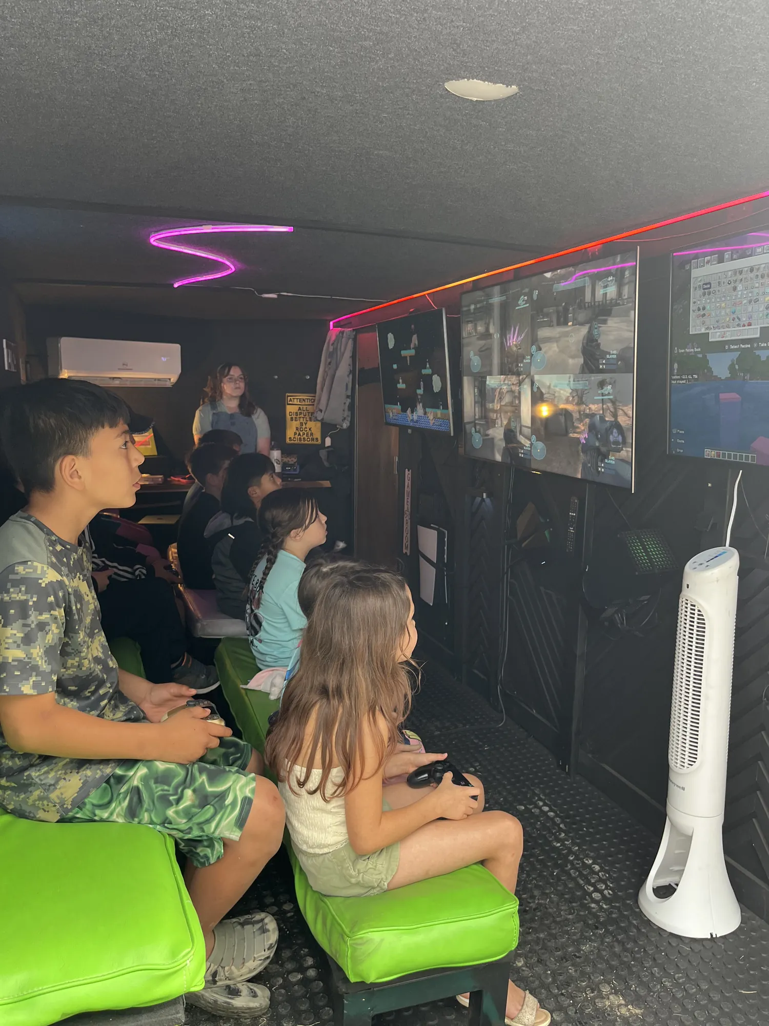 Kids playing video games on the trailer’s green benches at the Grain Theory block party