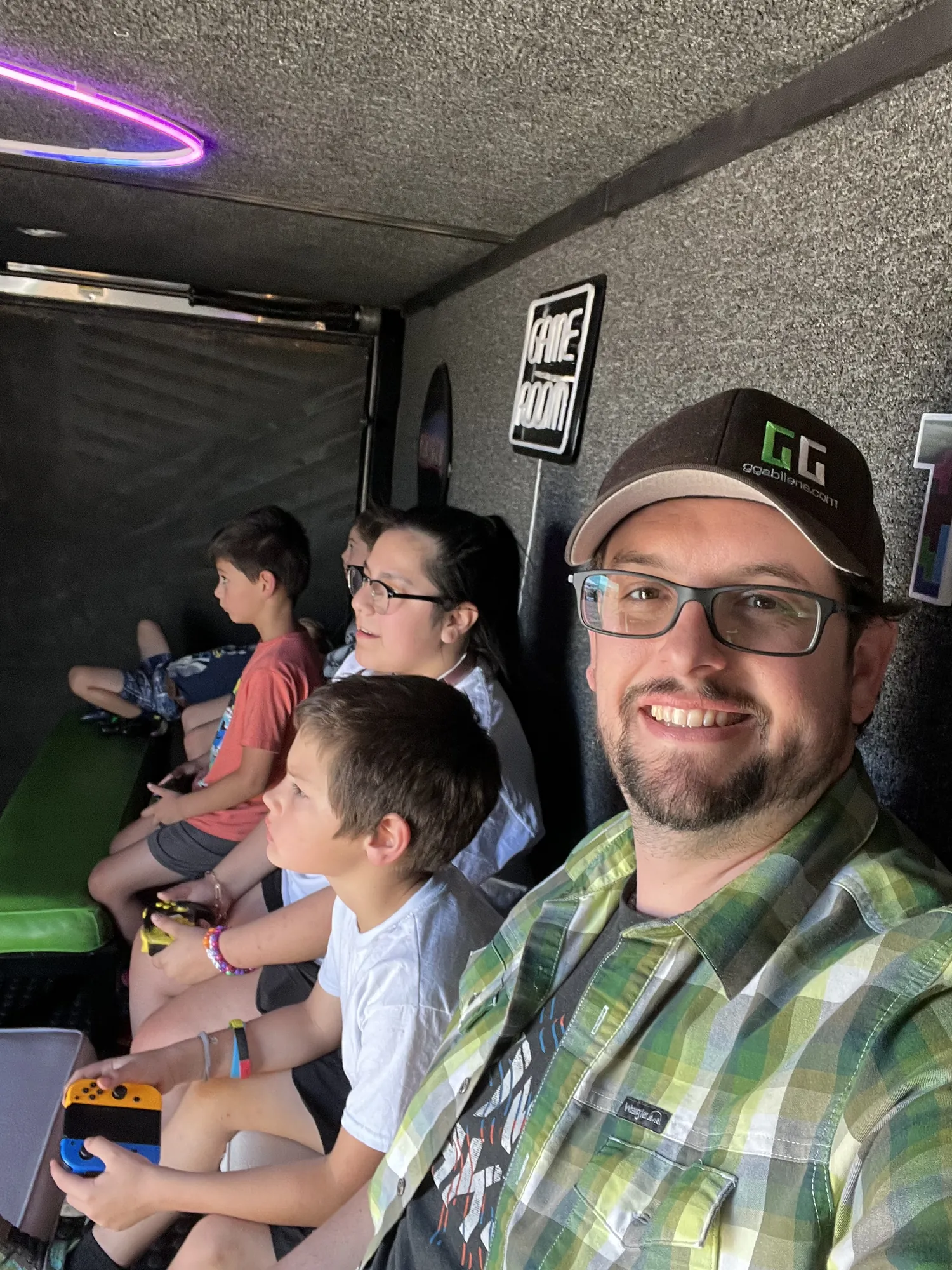 Our Game Coach smiling inside the trailer while kids play video games at a company family day