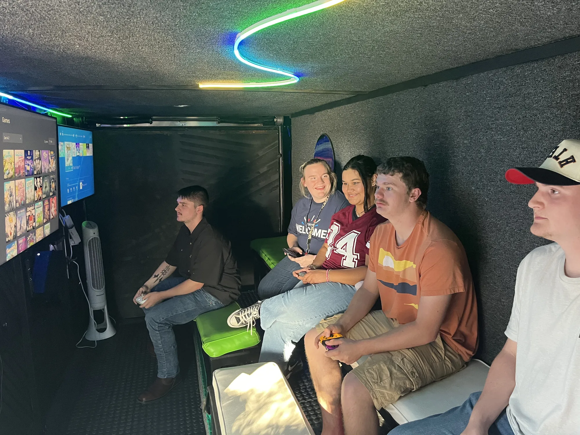Young adults laughing and playing video games together inside the trailer for a team building night