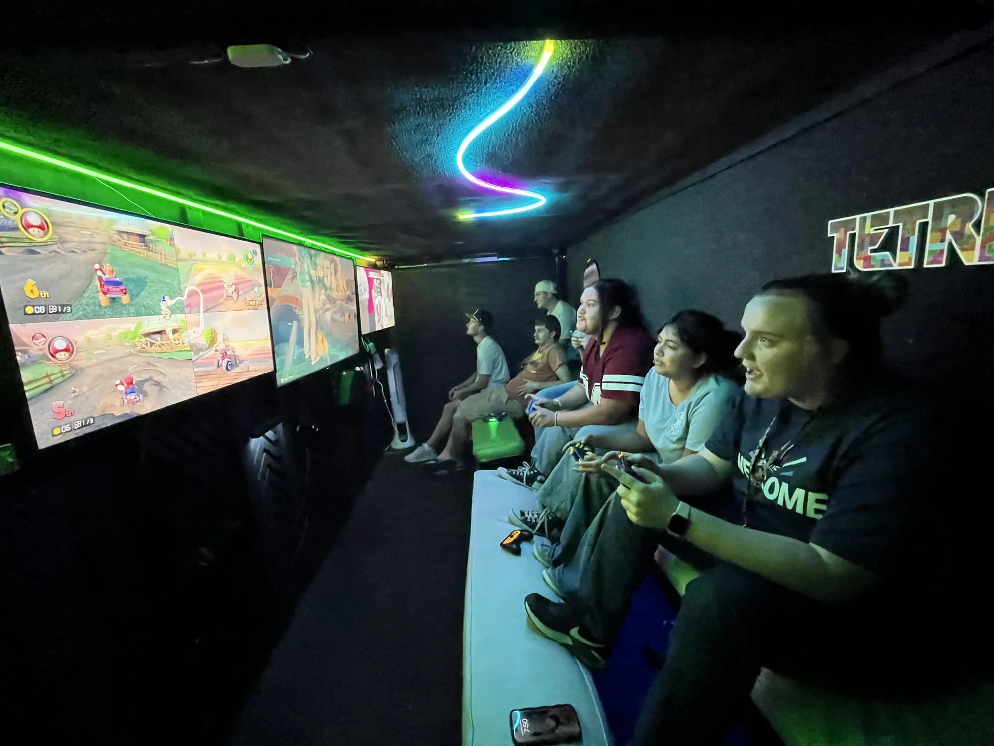 Grown-ups racing in Mario Kart on the trailer’s big screens during an evening event