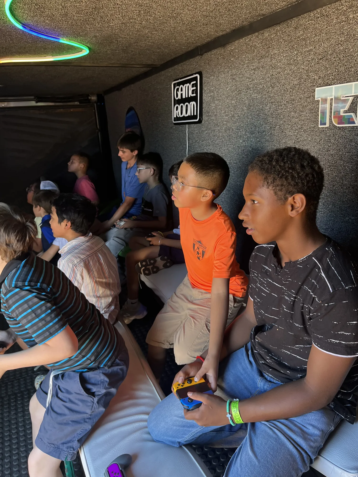 Kids gripping their controllers mid-game inside the air-conditioned trailer