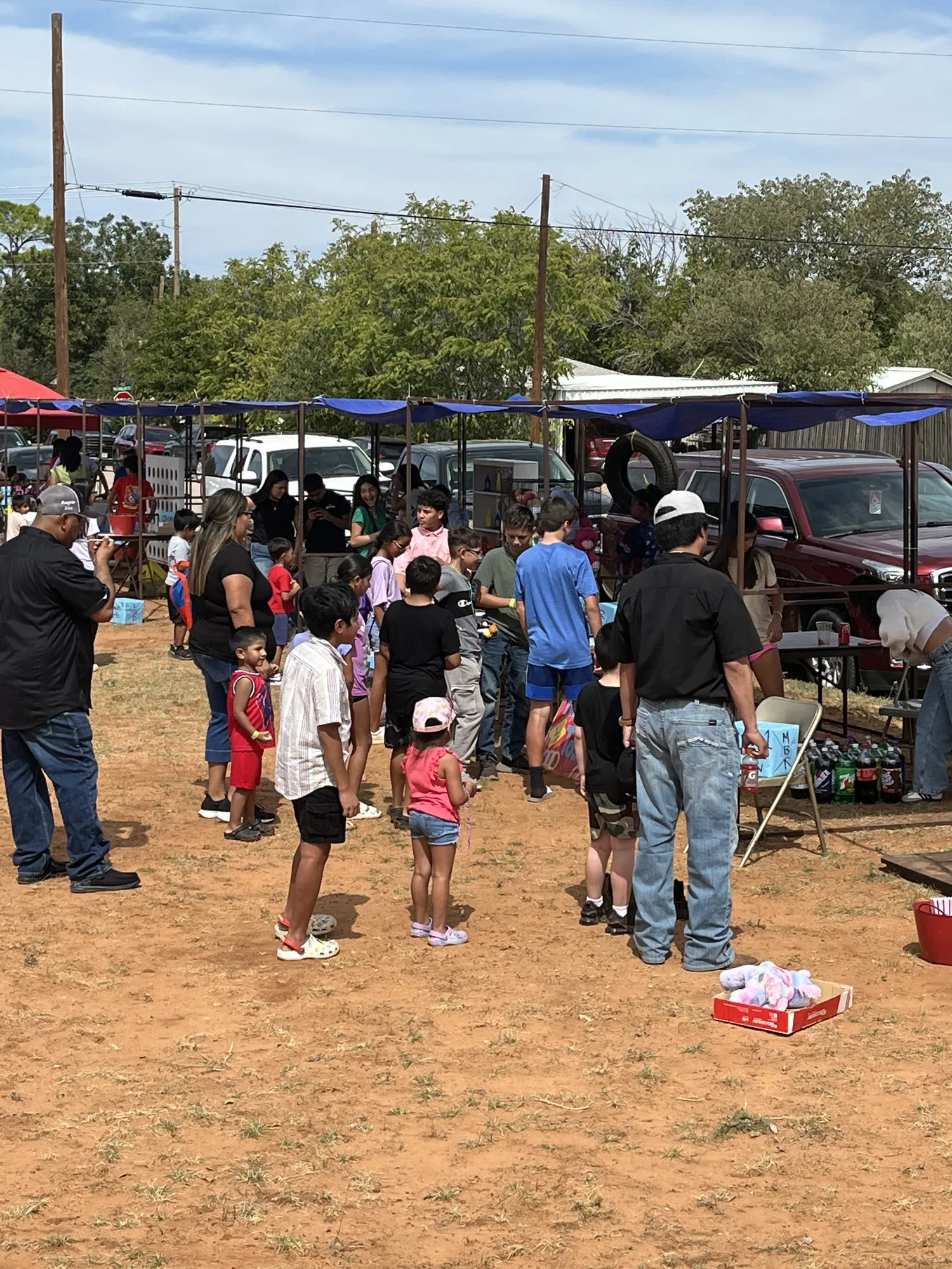 Families and kids gathered around game booths outside at a fall harvest festival
