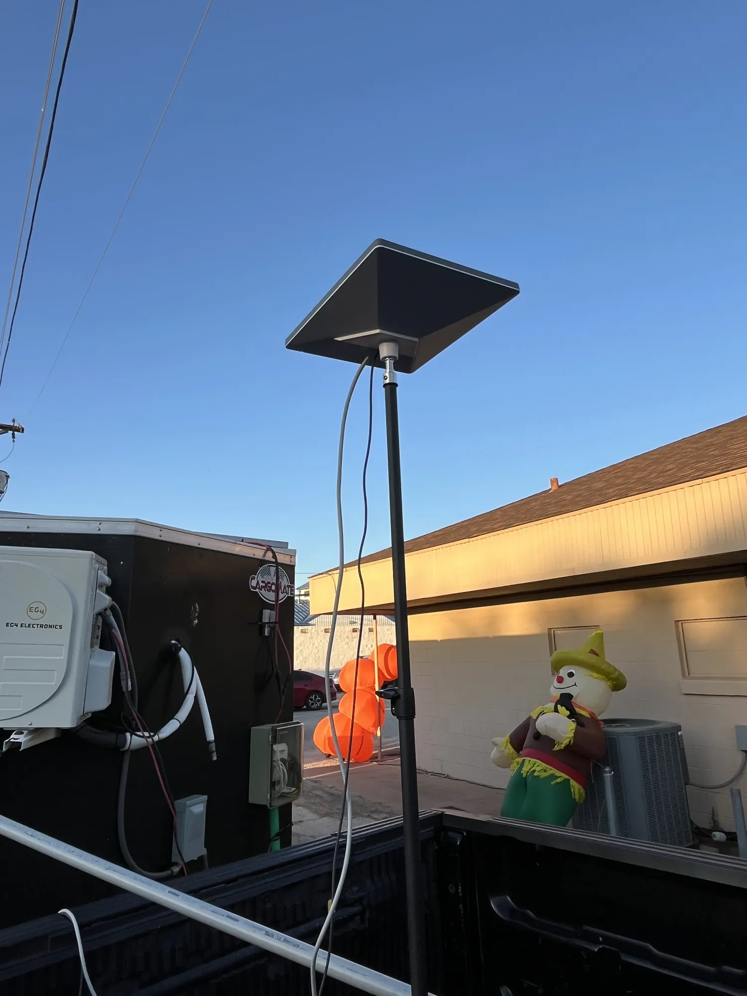 Our Starlink dish on its mast next to a scarecrow and fall decorations