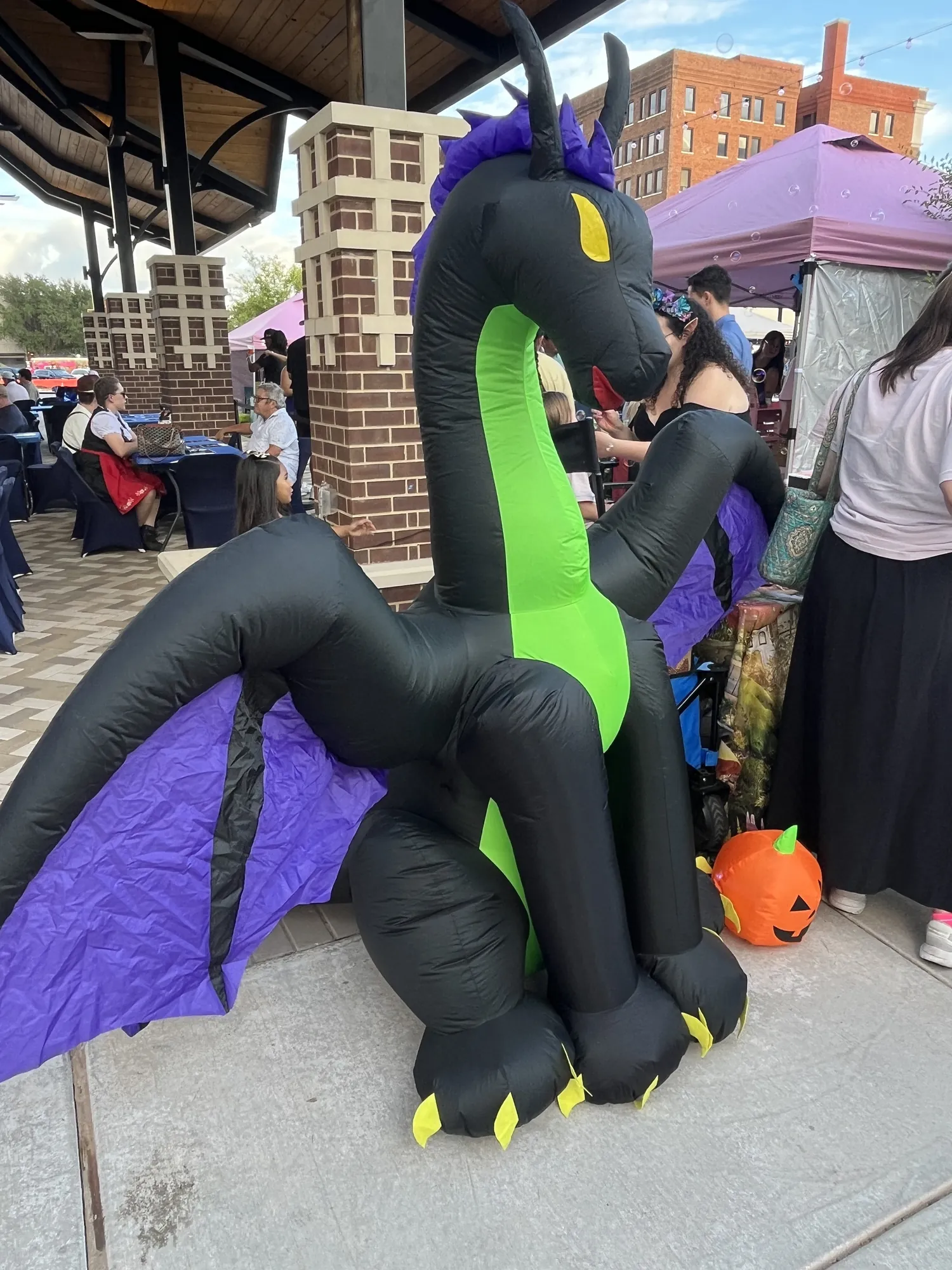 A big inflatable dragon beside a jack-o’-lantern at a fall festival in downtown Abilene