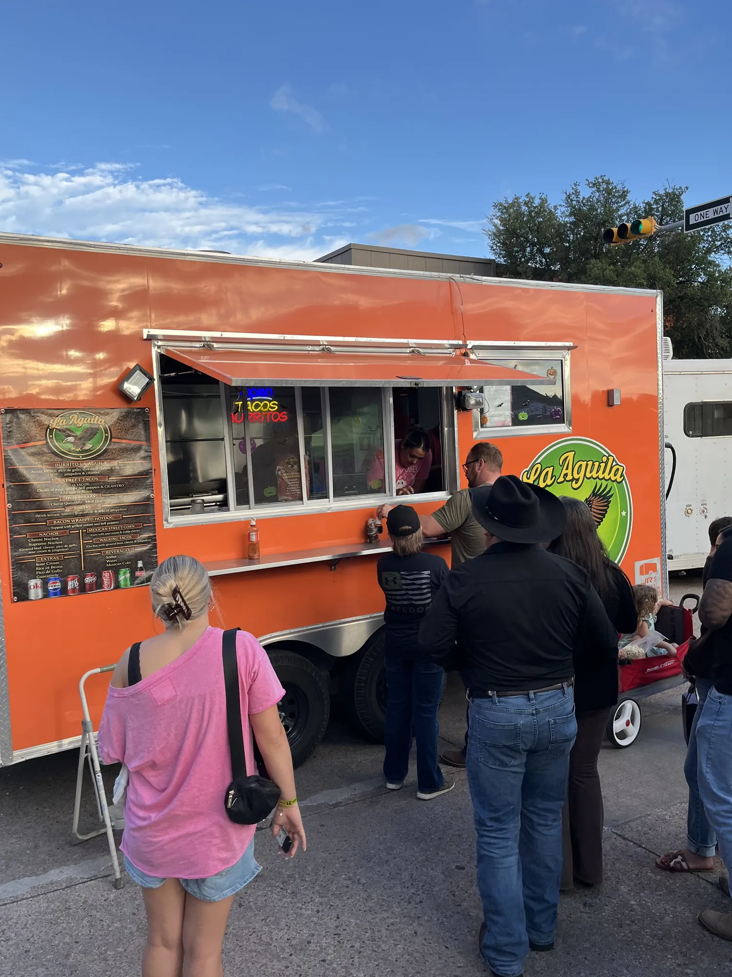 People lined up at the orange La Aguila taco truck