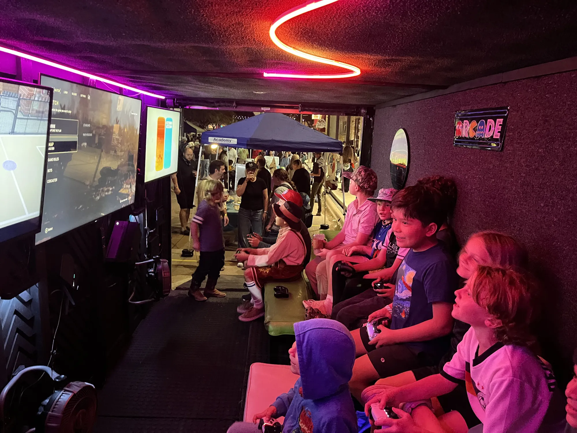 Kids playing video games on big screens inside the Green Games trailer at Downtown Oktoberfest in Abilene
