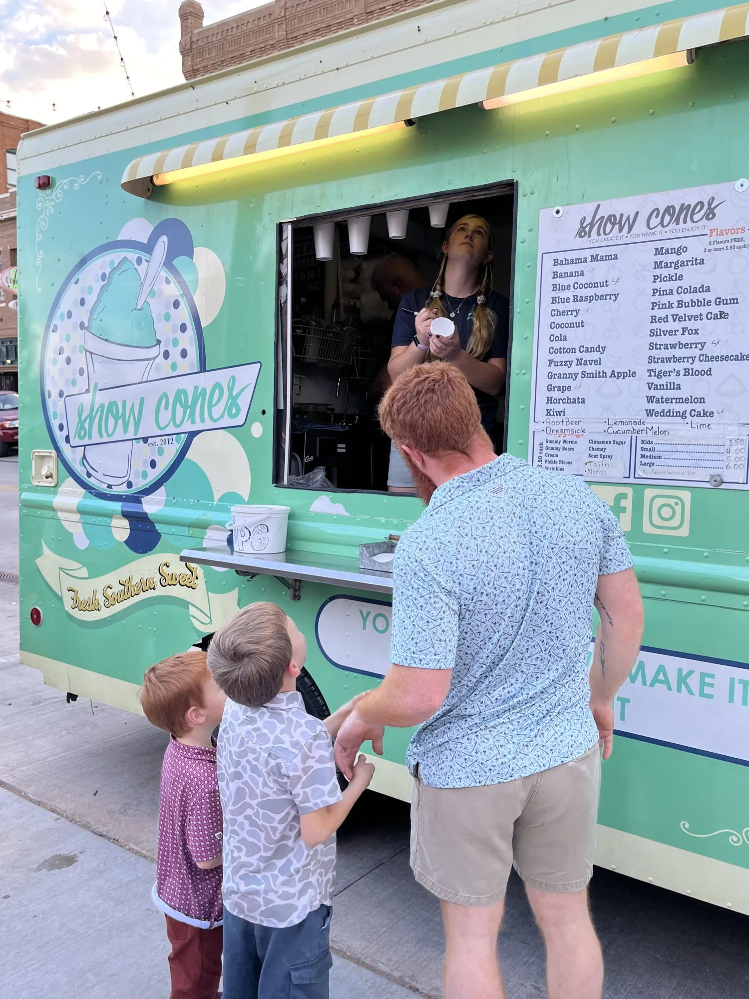 Kids ordering at the mint-green Show Cones snow cone truck