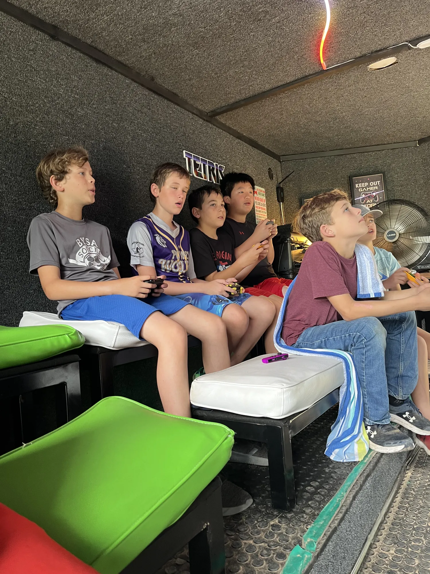 Elementary students cheering at the big screens inside the air-conditioned game trailer at a field day