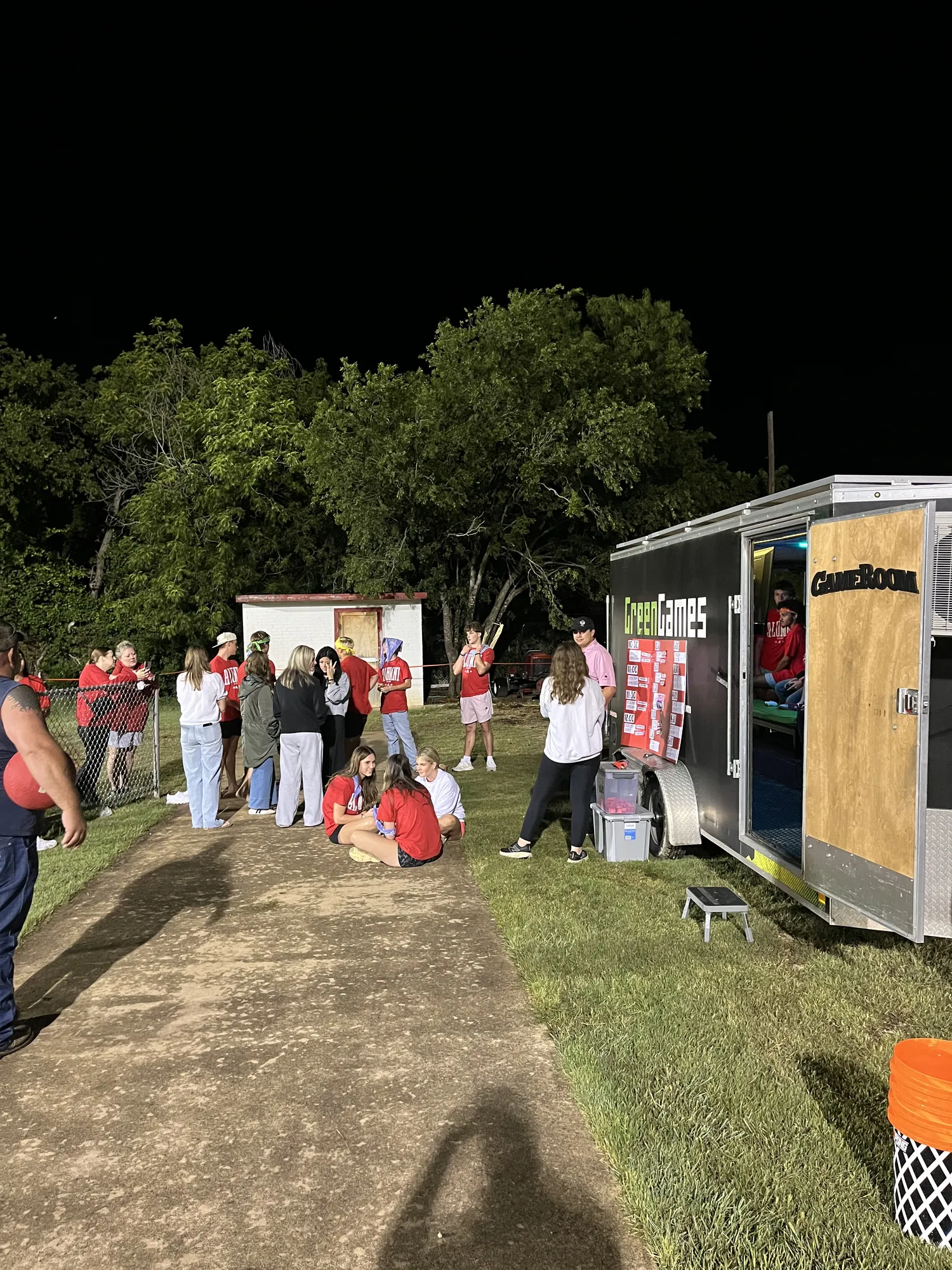 Students gathered on the grass beside the Green Games Abilene video game trailer late at night